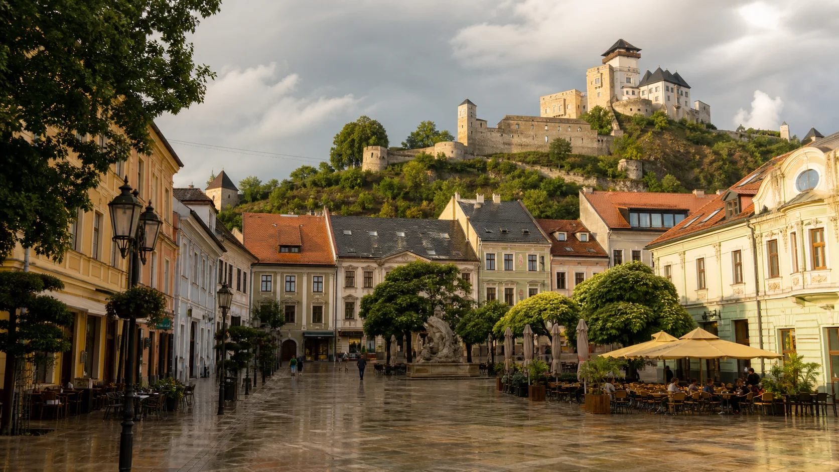 Trenčín Castle rising over pastel buildings and café tables on Mierové námestie