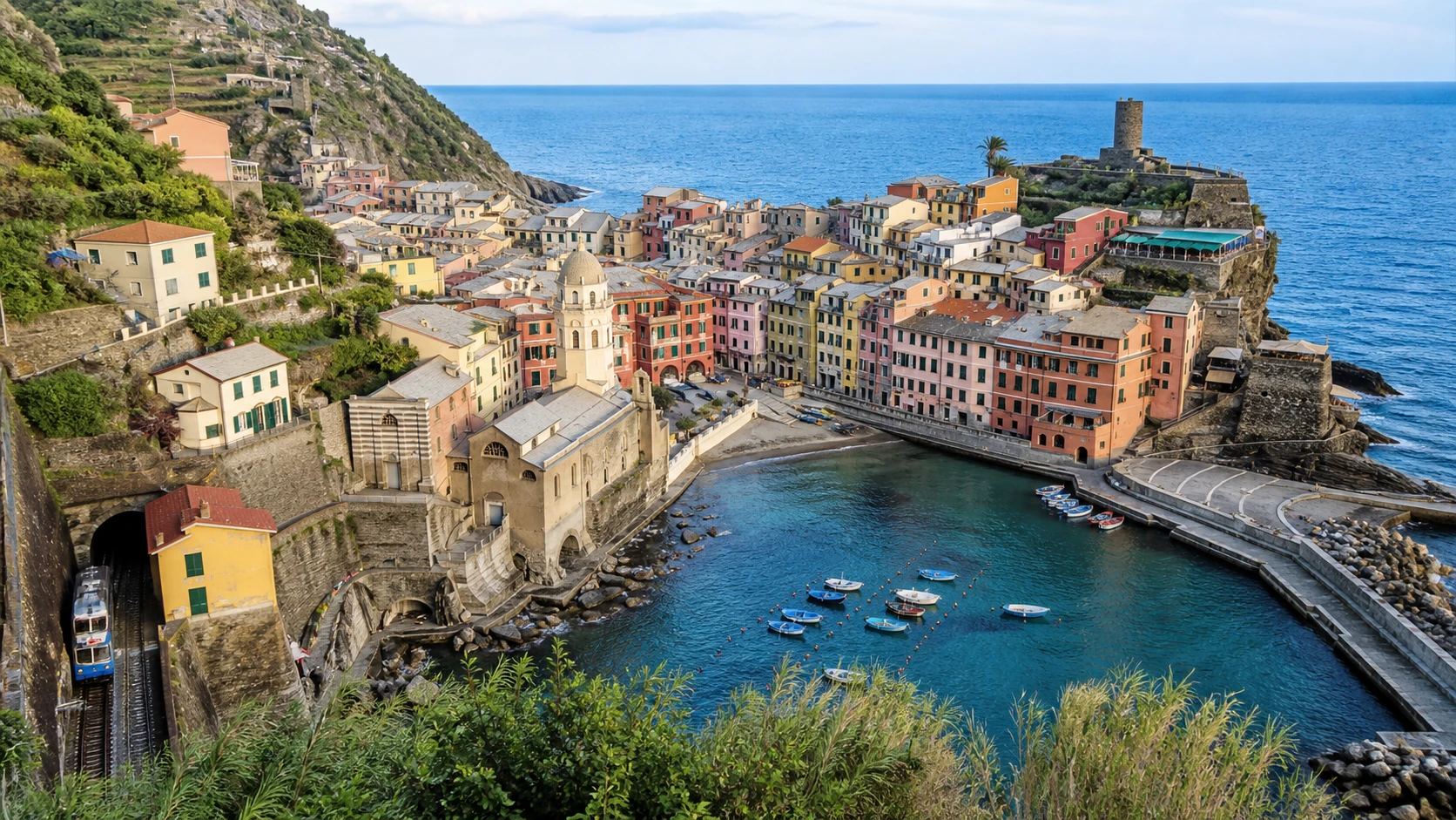 Vernazza harbor in Cinque Terre with pastel buildings and the railway entering the village